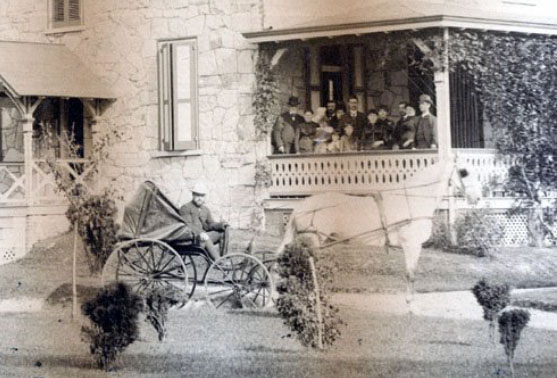 Colonel Taggart in his carriage with people on the porch